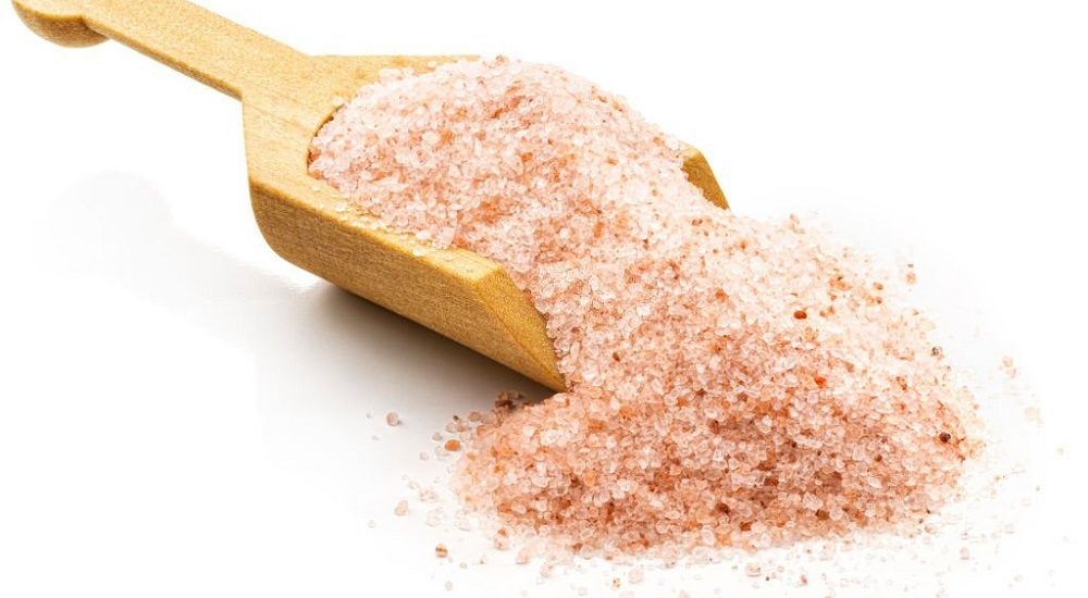 Himalayan salt in a wooden scoop. Isolated on a white background.