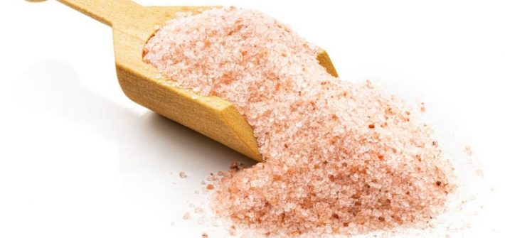 Himalayan salt in a wooden scoop. Isolated on a white background.